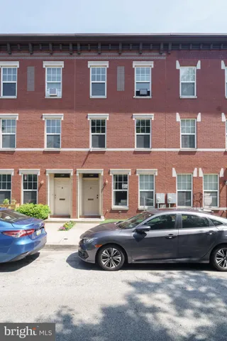 a front view of a building with lot of cars and trees