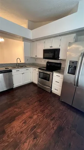 a kitchen with granite countertop a refrigerator and a stove top oven