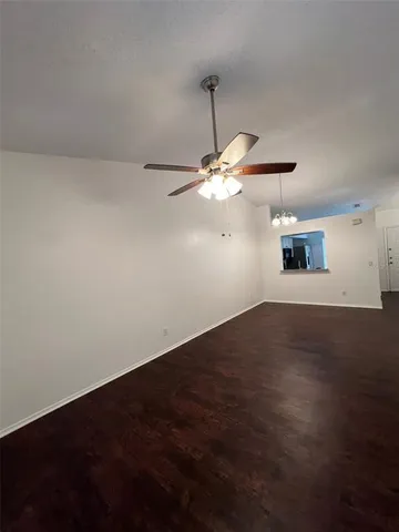 an empty room with wooden floor fan and window