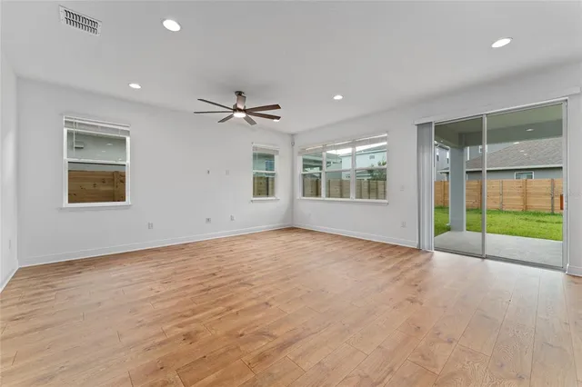 a view of an empty room with a window and wooden floor