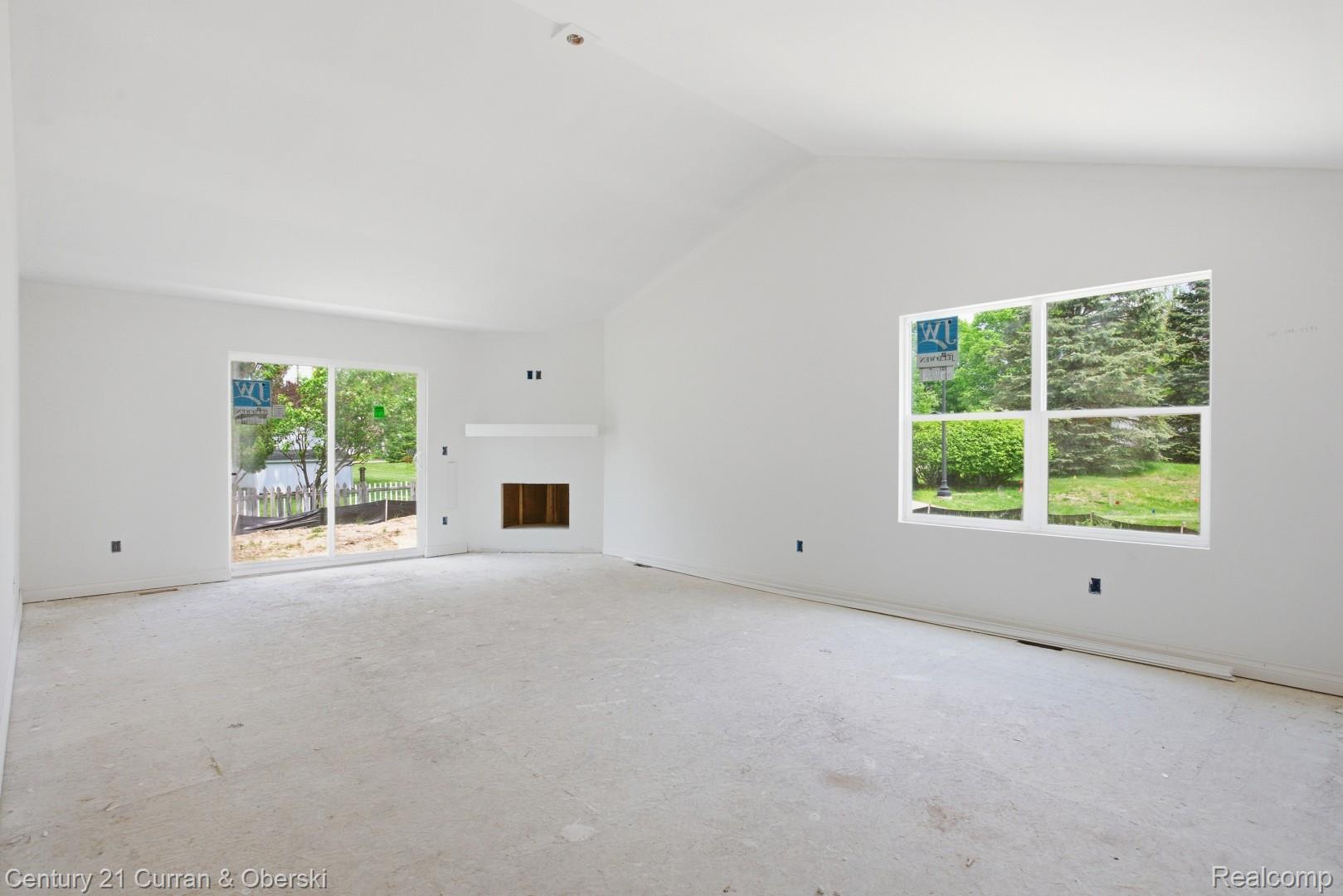 823 Nelson's Ridge Drive, Unit 13 Howell, MI 48843 - Photo 13 of 30 Spacious room featuring a vaulted ceiling and a built-in fireplace with a mantel