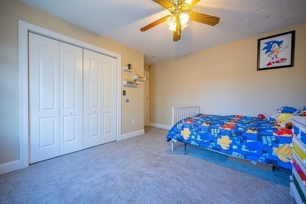 557 Cronin Road Warren, MA 01585 - Photo 16 of 28 a bedroom with a bed and a chandelier fan