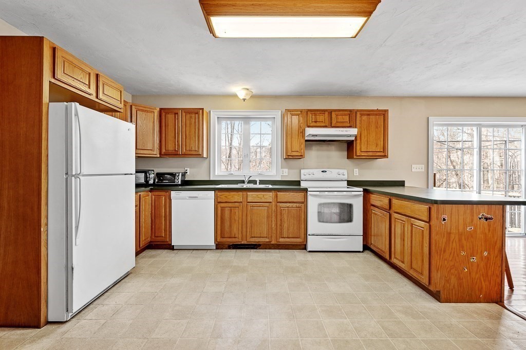 557 Cronin Road Warren, MA 01585 - Photo 3 of 28 a kitchen with white cabinets and white appliances