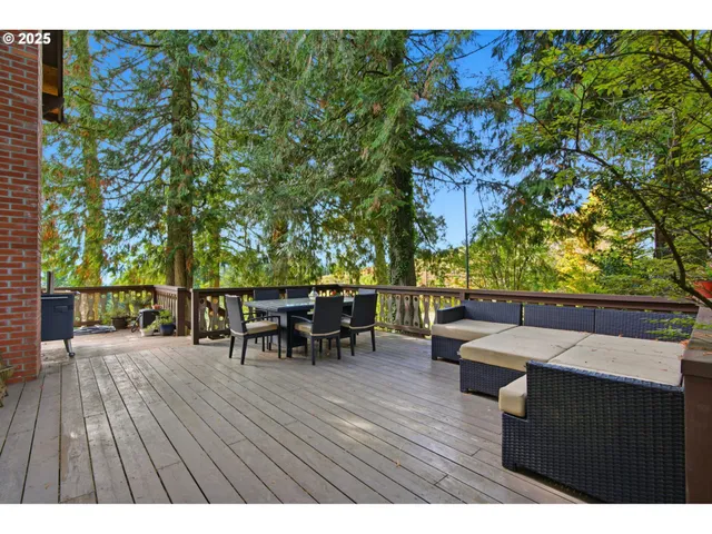 a view of a patio with couches and table and chairs with wooden floor and fence