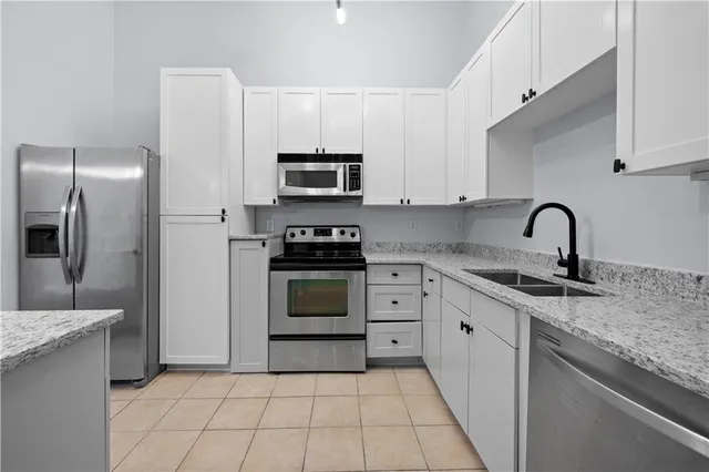 a kitchen with granite countertop white cabinets stainless steel appliances and a sink