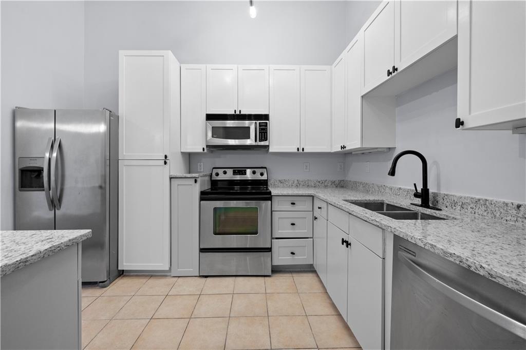 400 17th Street Northwest, Unit 1113 Atlanta, GA 30363 - Photo 9 of 37 a kitchen with granite countertop a sink stove and refrigerator