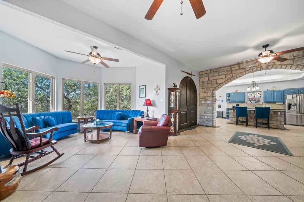 209 Lakeview Circle Spring Branch, TX 78070 - Photo 7 of 40 Living room featuring arched walkways, light tile patterned floors, and ceiling fan with notable chandelier