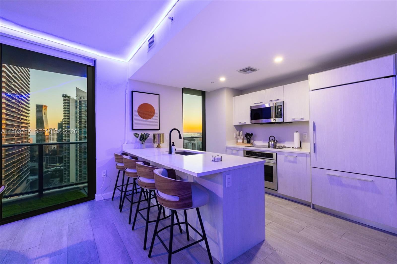 45 Southwest 9th Street, Unit 2803 Miami, FL 33130 - Photo 59 of 66 a kitchen with a refrigerator a stove top oven a sink dishwasher and a dining table with wooden floor
