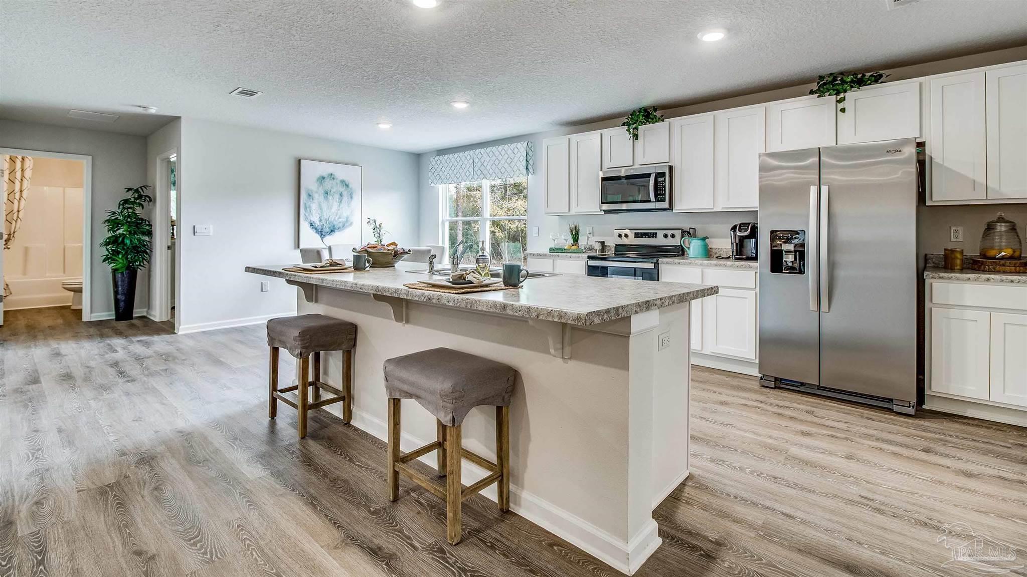 9728 Dutton Lane Milton, FL 32583 - Photo 13 of 31 a kitchen with stainless steel appliances a dining table chairs refrigerator and microwave