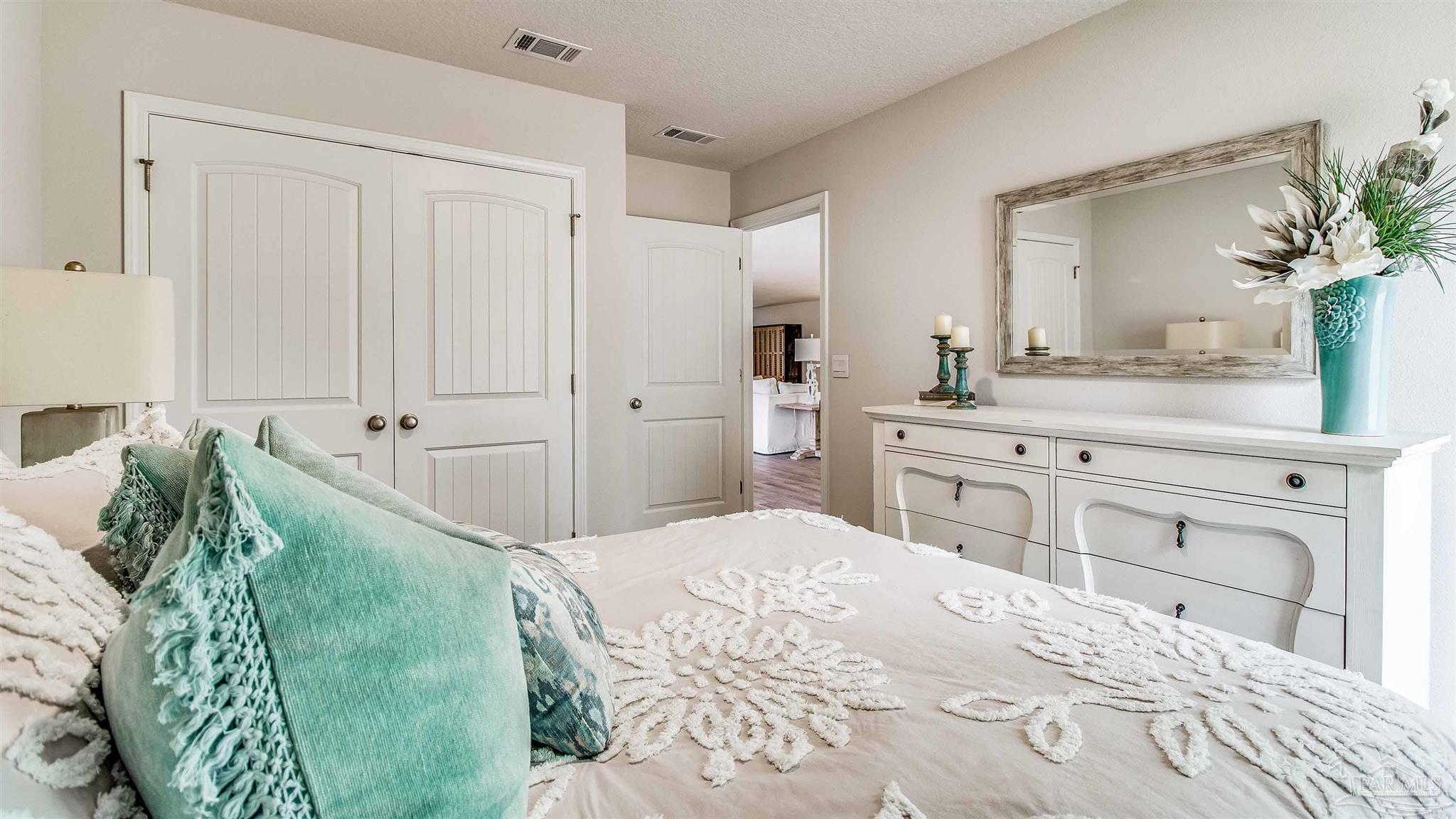 9728 Dutton Lane Milton, FL 32583 - Photo 18 of 31 a spacious bedroom with a bed and a mirror