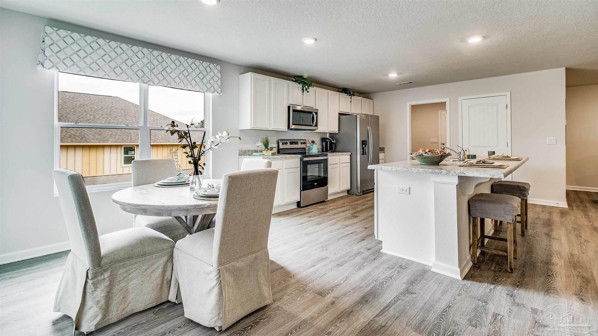 9728 Dutton Lane Milton, FL 32583 - Photo 8 of 31 a view of kitchen with granite countertop microwave a stove a sink a dining table and chairs