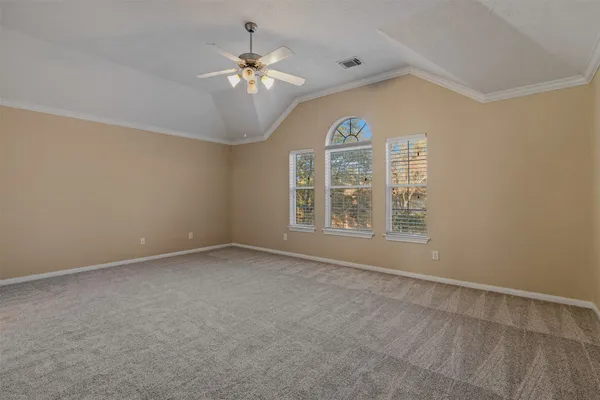 an empty room with chandelier fan and windows