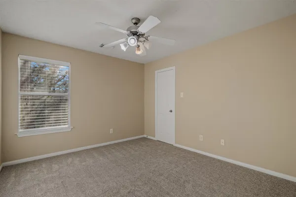a view of an empty room with chandelier fan and fire place