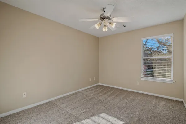 a view of an empty room with chandelier fan and fire place