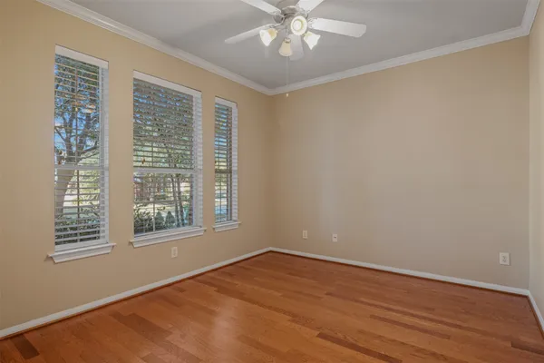 a view of an empty room with wooden floor and a window