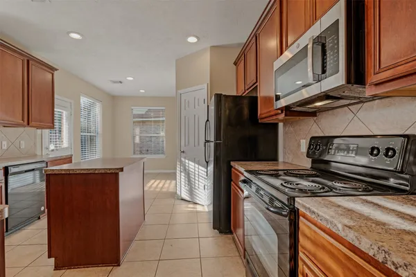 a kitchen with stainless steel appliances granite countertop a stove a refrigerator and a microwave