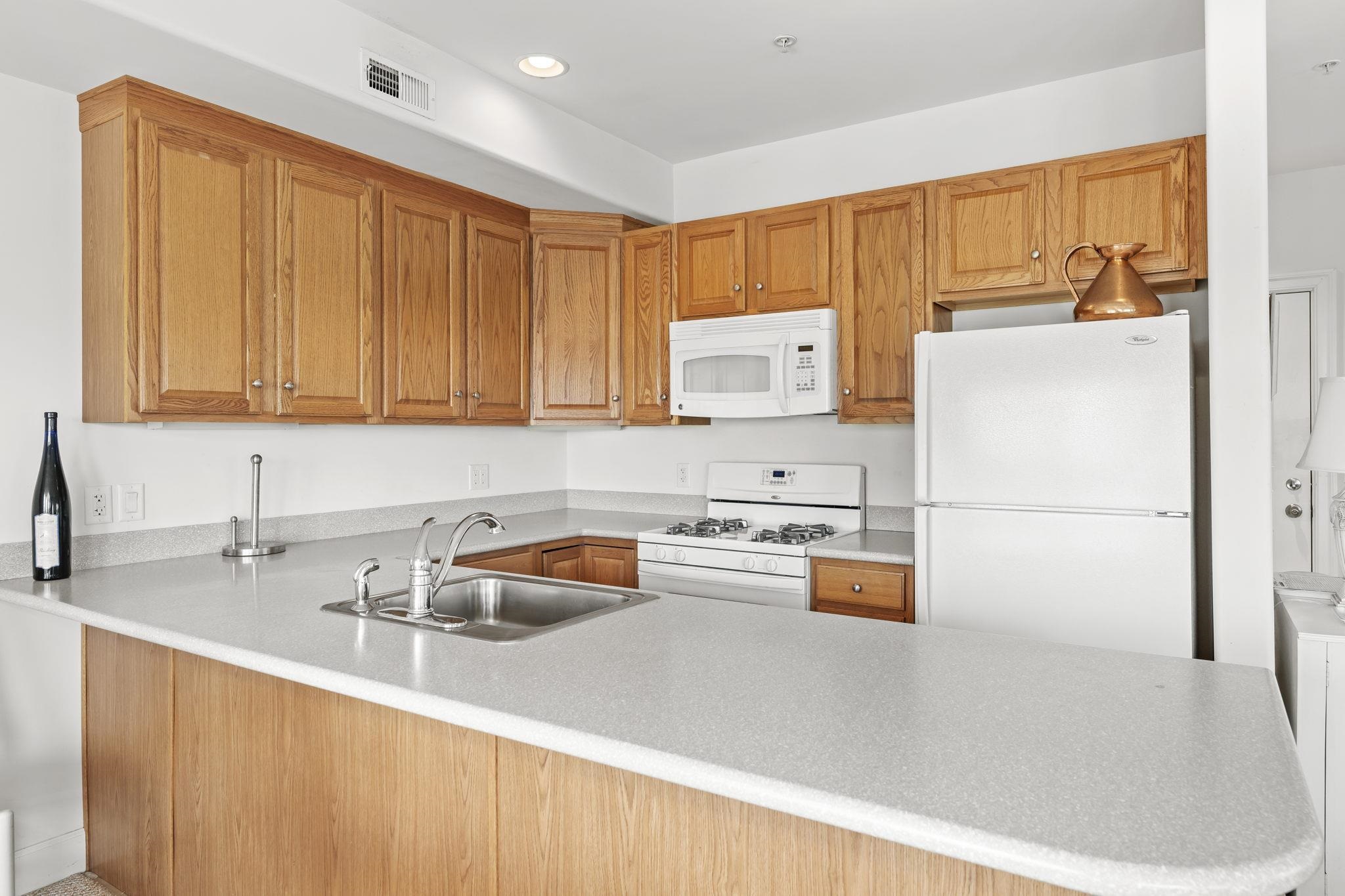 700 Ocean Drive, Unit E4 Avalon, NJ 08202 - Photo 15 of 31 a kitchen with stainless steel appliances a refrigerator a sink a stove and wooden cabinets