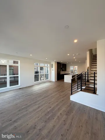 an empty room with wooden floor and kitchen view