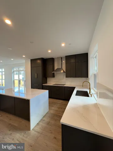 a large kitchen with kitchen island a sink dishwasher a stove and a refrigerator with wooden floor