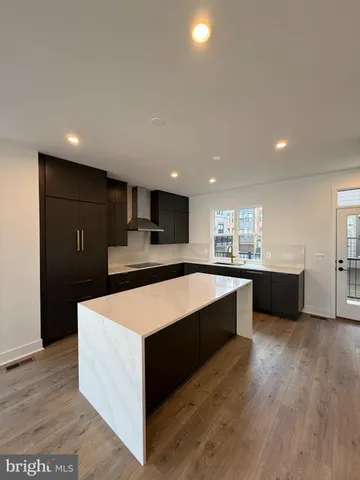 a large kitchen with kitchen island a sink dishwasher a stove and a refrigerator with wooden floor