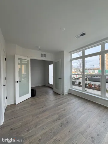 a view of an empty room with a window and wooden floor
