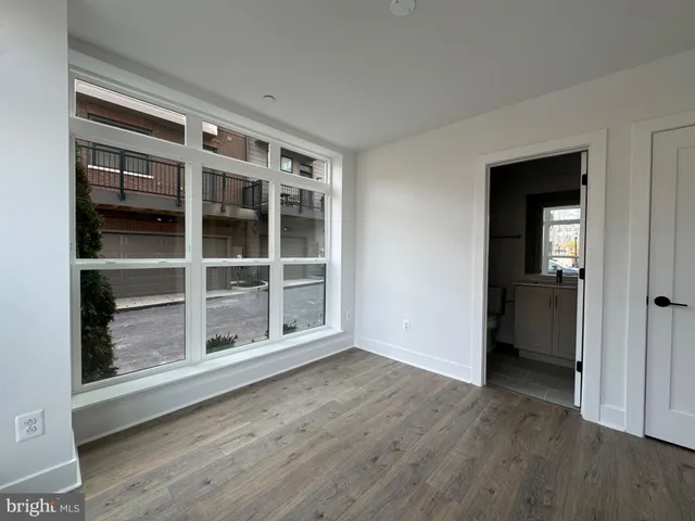 a view of an empty room with wooden floor and windows