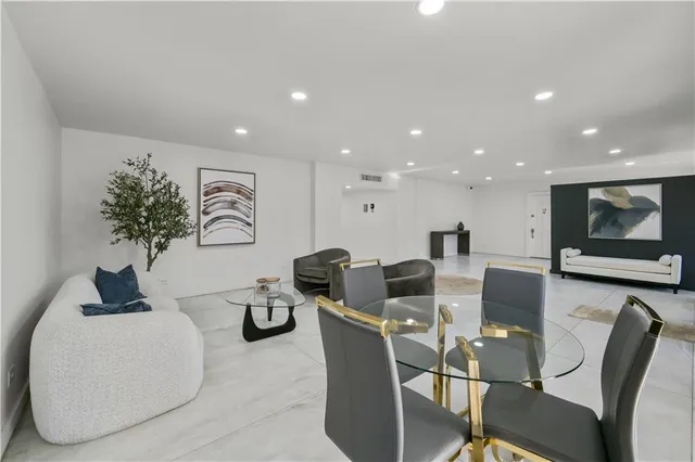 a living room with couches and kitchen view with wooden floor