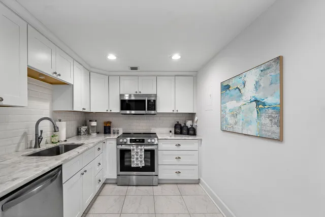 a kitchen with granite countertop white cabinets stainless steel appliances and a sink