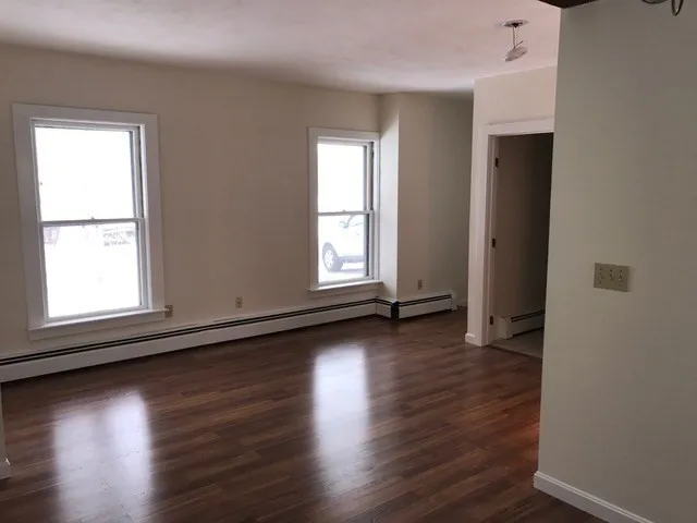 a view of an empty room with wooden floor and a window