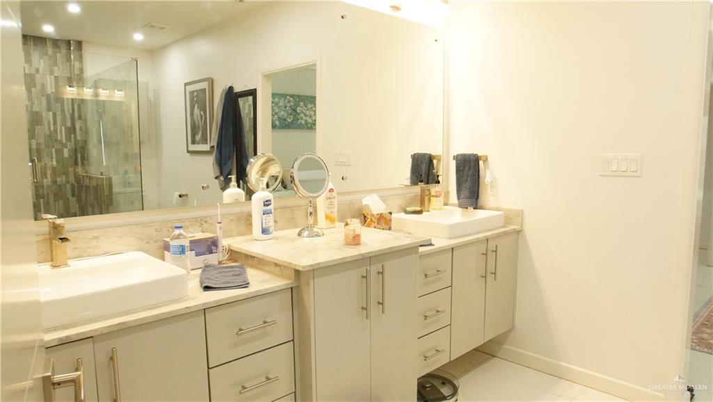 414 Ric Mar Street Edinburg, TX 78541 - Photo 23 of 36 Contemporary bathroom featuring dual vessel sinks with gold-finish faucets, light-toned cabinetry, and integrated vanity lighting