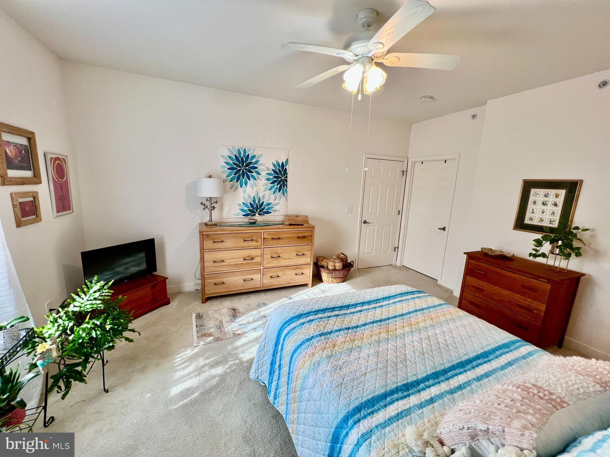 30611 Cedar Neck Road, Unit 2306 Ocean View, DE 19970 - Photo 15 of 37 a bedroom with a bed potted plant and a chandelier