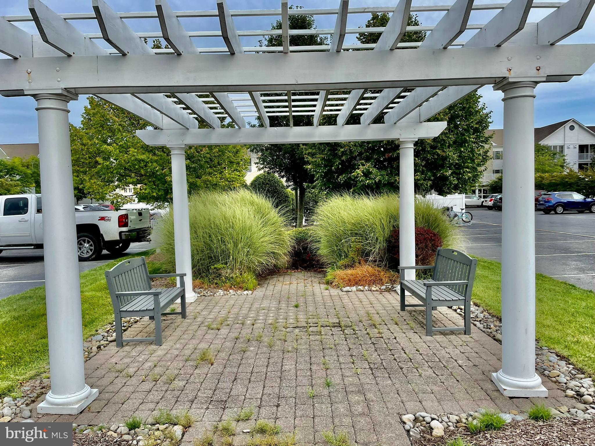 30611 Cedar Neck Road, Unit 2306 Ocean View, DE 19970 - Photo 30 of 37 a view of a patio with table and chairs potted plants and floor to ceiling window