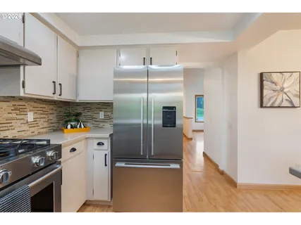 a kitchen with stainless steel appliances granite countertop a refrigerator a stove and a sink with wooden floor