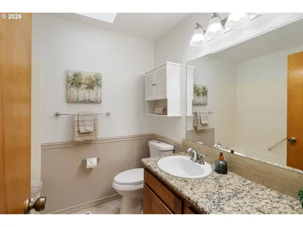 a bathroom with a granite countertop sink a toilet a mirror and shower