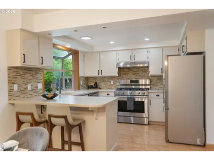 a kitchen with kitchen island white cabinets a refrigerator a stove a sink and a oven with wooden floor