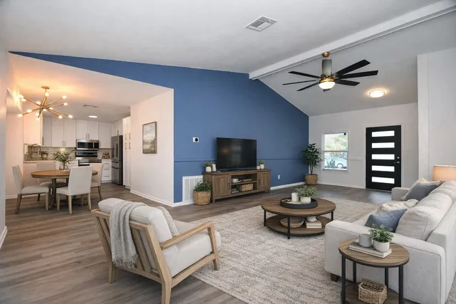 a living room with furniture a flat screen tv and kitchen view