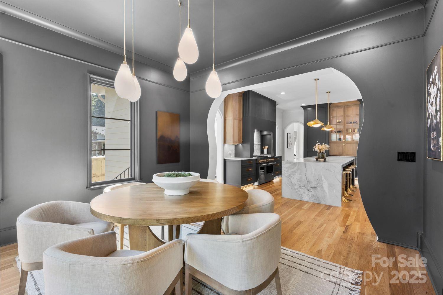 919 Lansdowne Road Charlotte, NC 28270 - Photo 3 of 3 a dining room with wooden floor a chandelier a wooden table and chairs