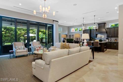 595 Regatta Road Naples, FL 34103 - Photo 18 of 40 Spacious open-concept interior featuring light-toned flooring, a modern chandelier, extensive glass patio doors, recessed lighting, and a kitchen with dark cabinetry and an island