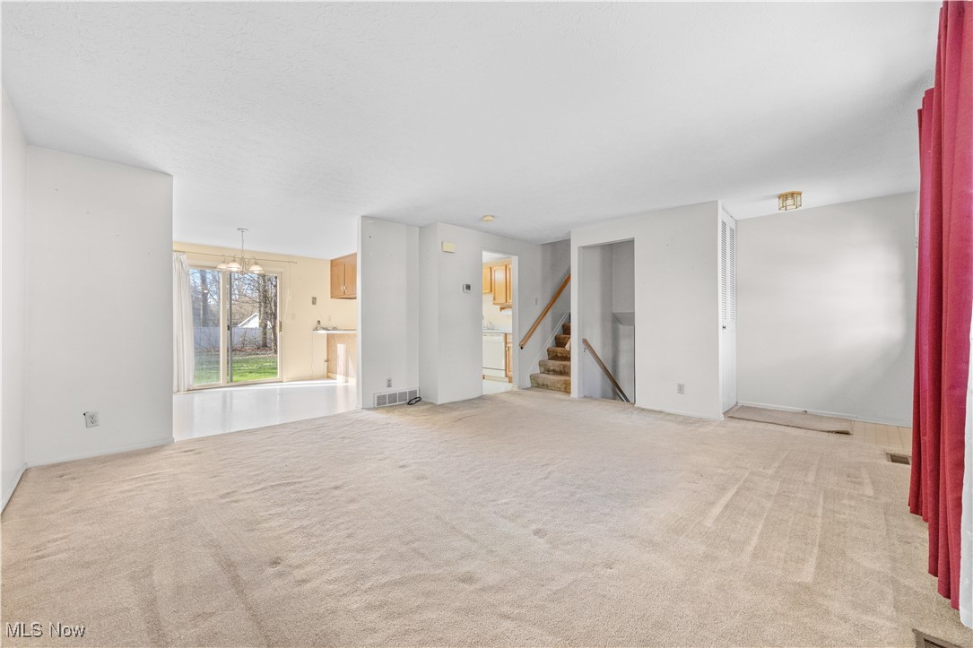 4301 Baird Road Stow, OH 44224 - Photo 5 of 50 Unfurnished living room with stairs, visible vents, carpet, and a chandelier
