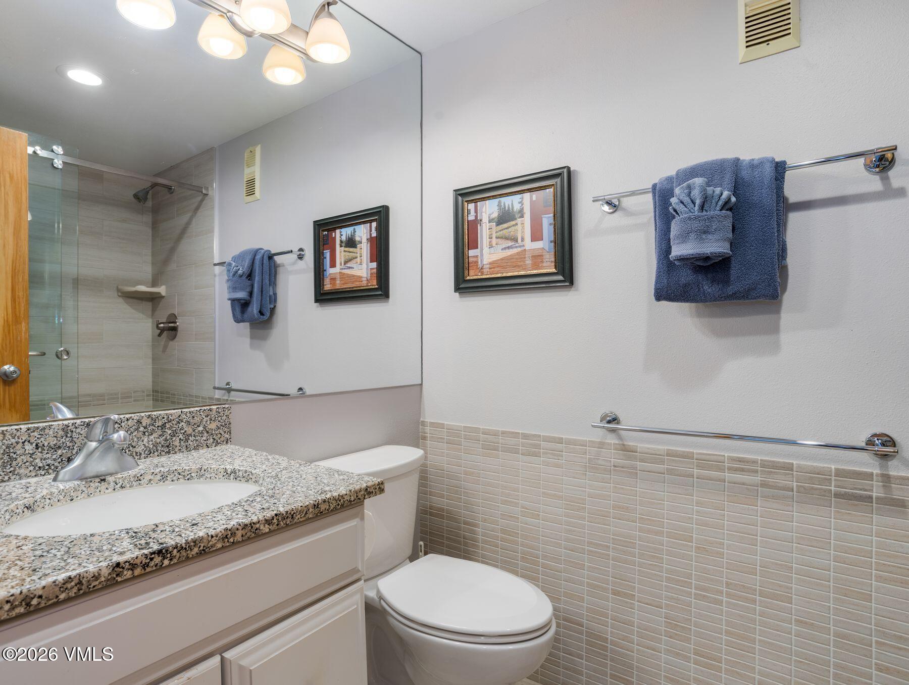 1100 North Frontage Road West, Unit 1503 Vail, CO 81657 - Photo 19 of 32 a bathroom with a granite countertop sink a toilet and mirror