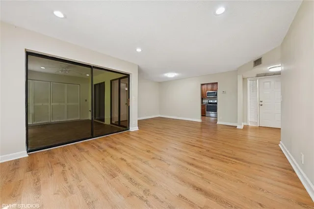 a view of an empty room with wooden floor and a bathroom