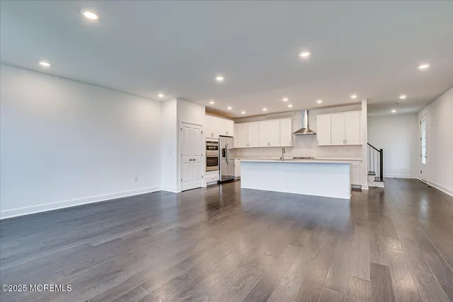 a view of kitchen with kitchen island wooden floor center island and stainless steel appliances