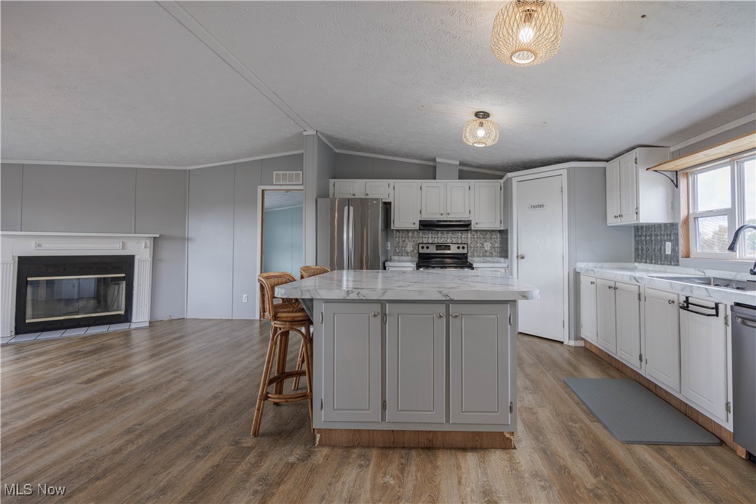540 Wine Road Elizabeth, WV 26143 - Photo 49 of 49 Kitchen with a kitchen island, a kitchen breakfast bar, tasteful backsplash, open floor plan, and light wood-type flooring