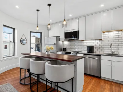 a kitchen with stainless steel appliances granite countertop a sink a stove a kitchen island with chairs and wooden floor