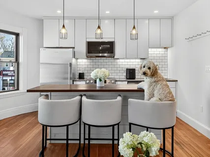 a kitchen with stainless steel appliances granite countertop a table chairs and a refrigerator