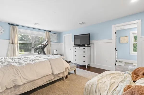 a bedroom with bed and flat tv with wooden floor