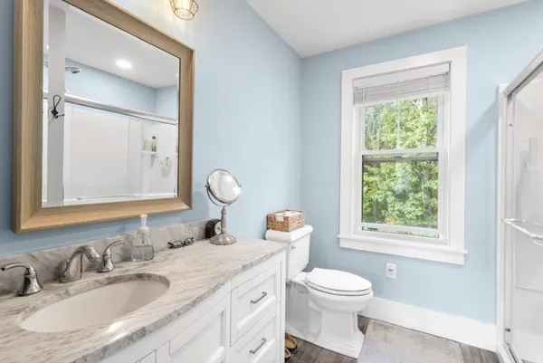 a bathroom with a granite countertop sink toilet a large mirror and a window