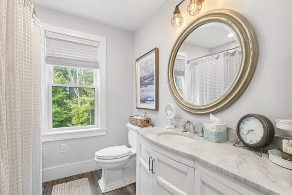 a bathroom with a granite countertop toilet a sink and a mirror