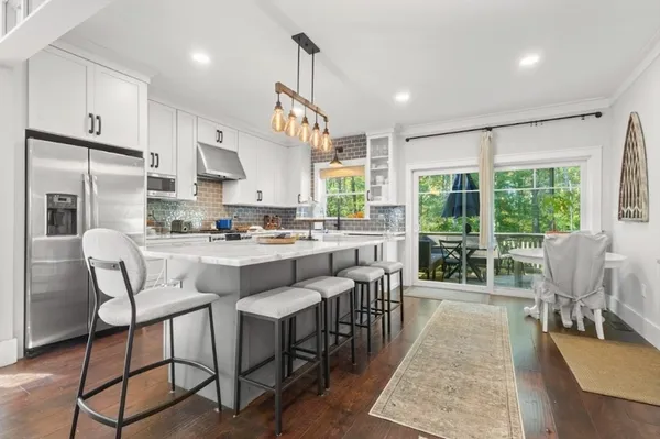 a kitchen with stainless steel appliances granite countertop a table chairs and a view of living room
