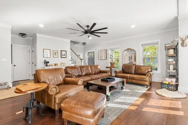 a living room with furniture a ceiling fan a lamp and a window